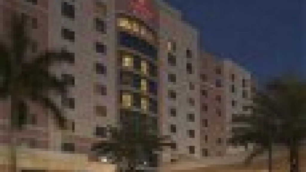 Building exterior at night with palm trees and tropical landscaping illuminated by lights